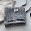 Close-up of wool blended scarf with premium woven brand label and warm knitted texture - Gray