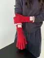 Detailaufnahme roter Strickhandschuhe mit weißem Bonjour-Webetikett am Ärmelbund des Handschuhs - Rot