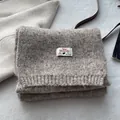 Close-up of brown wool blend knitted scarf texture with premium branded woven label - Milk Tea Apricot