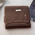 Close-up of soft brown wool scarf featuring ERET WOOL label and silver B charm detail - Coffee