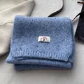 Detail of wool blend knitted scarf in sea salt blue with speckled texture and brand label - Sky Blue