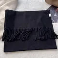 Detail shot of black 100% pure wool scarf with fringe and quality certification tag - Black