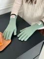 Details von minzgrünen Strickhandschuhen mit Bonjour-Etikett und braunen Bündchen - Bohnengrün