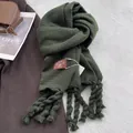 Detail of dark green cashmere-feel scarf showing thick twisted fringe and leather logo patch - Forest Green