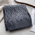 Detail of the 100% merino wool knit texture and material label on a grey scarf - Gray