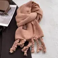 Close-up of thick pink-orange cashmere-feel scarf with tassels and leather brand label - Pink