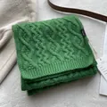 Detail view of green 100% merino wool scarf showing classic chunky cable knit and label - Green