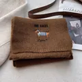 Close-up of brown knit scarf with detailed dachshund embroidery and heart pattern - Caramel color