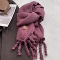 Detalle de bufanda gruesa de color púrpura oscuro con borlas y etiqueta de marca - Rosa Frambuesa