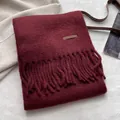 Détail d'une écharpe en maille bordeaux avec étiquette en cuir et franges torsadées fines - Rouge Ancorra