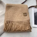 Detalle de bufanda de lana con borlas de flecos y etiqueta de marca cuadrada premium - 180x30cm / Camel