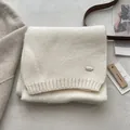 Dettaglio sciarpa di lana a maglia color crema con placchetta in metallo e coste - Avorio