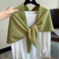 Detail eines weichen grasgrünen Strickschals aus Wolle über einem weißen Shirt - Grün