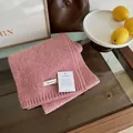 Close-up of pink wool scarf texture with 100% Wool label on a wooden surface - Dusty Pink
