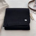 Detail of black knit scarf featuring silver metal logo and soft wool texture finish - Black