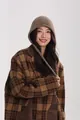 Detailansicht der braunen Wollstrickmütze mit Ohrenklappen und Vintage-Karomantel - Camel