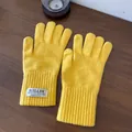 Detail of yellow knit gloves with touch screen finger opening on a wooden background - Yellow