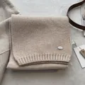 Detailed close-up of oatmeal wool blend knit scarf with metallic brand tag and soft texture - Off White