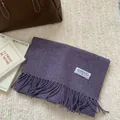 Gros plan sur l'écharpe en laine violette avec franges et étiquette de la marque - 180x30cm / Violet