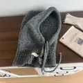 Detailed close-up of dark grey wool blend knitted balaclava with button and drawstring - Gray