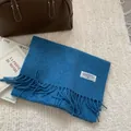 Detail of light blue pure wool scarf featuring fringe ends and a branded woven label - 180x30cm / Sea Salt Blue