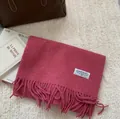 Detail of wool fringe scarf in deep pink on a white rug with premium leather bag and magazine - 180x30cm / Raspberry Pink