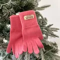 Close-up of pink knit gloves with ribbed cuffs and brand tag on winter tree branches - Pink