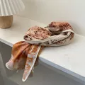 Detail of herringbone silk wool scarf with tropical floral print on a white wood surface - 140*40cm / Orange