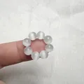 Dettaglio di un anello di perle di quarzo al dito con perle bianche traslucide rotonde - Occhio di Gatto Bianco