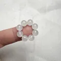 Dettaglio ravvicinato di un anello di perle di agata bianca naturale sul dito - calcedonio bianco