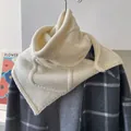 Detail eines cremefarbenen Strickschals aus Wolle mit Knopf auf einem grauen Mantel - Elfenbein