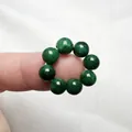 Vista macro di 8 perle tonde in giada naturale verde scuro disposte in cerchio su pelo - Imitazione Maw Sit Sit