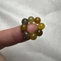 Macro di anello in agata con venature di drago su dito e sfondo di tessuto bianco - Agata Vena di Drago