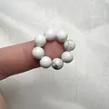 Dettaglio dell'anello elastico con perline di turchese bianco e trama marmorea - Howlite