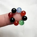 Vista macro dettagliata di un anello elastico fatto di otto perle di pietra naturale - Agata Colorata
