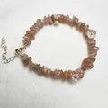 Detail of natural stone bead bracelet featuring orange gravel and white floral charms - Sunstone