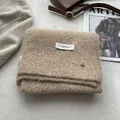 Detail of oatmeal wool scarf featuring a soft plush texture and minimalist brand label - Khaki
