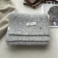 Detail of gray wool knit scarf showing soft texture, brand label and metal button ornament - Light Gray