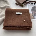 Detail view of coffee wool scarf with premium woven label and golden metal button - Coffee