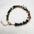 Detailed shot of handmade bracelet featuring natural gemstones, flower charms, and gold clasp - Tourmaline