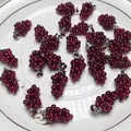 Macro detail of garnet grape pendants with gold-plated clasps on a ceramic tray - Silver Color Buckle