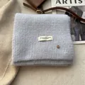 Detail of soft blue wool knit scarf with ribbed texture and decorative woven label - Azure Blue