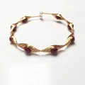 Detail of handmade wire-wrapped gold bracelet with red garnet beads and a white pearl accent - Evil Eye Style / Gold With Red Pearl