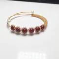 Detailed close-up of gold-plated open bracelet with red cinnabar beads and white pearls - Wave Wrapped Style / Gold With Red Pearl