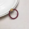 Close-up of beaded garnet ring with rutilated quartz and gold spacers on ceramic plate - Garnet Style