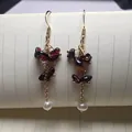 Vue détaillée des boucles d'oreilles dorées avec éclats de grenat et perles baroques - Style Grenat