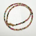 Gros plan d'un collier en perles de tourmaline colorées avec fermoir mousqueton doré - Collier Perles Moyennes