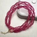 Faceted deep pink spinel beaded necklace with gold lobster clasp on beige fabric background - Faceted Round Beads / Red Spinel (Rose Red)