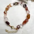 Primer plano de una pulsera de cristales naturales coloridos con cierre de mosquetón dorado - Pulsera de Cuarzo Hematoideo Koi