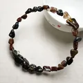 Détail d'un bracelet en perles de cristal naturel avec pierres sombres et touches dorées - Pietersite